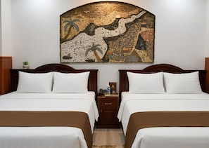 A hotel room with two beds, a nightstand with a phone and a bottle, and a wall art piece. - Happy Home (Ho Chi Minh City)