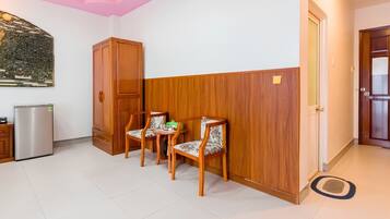 A room with a wooden cabinet, two chairs, a refrigerator, and a door.
