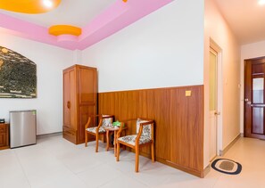A room with a wooden cabinet, two chairs, a refrigerator, and a door. - Happy Home (Ho Chi Minh City)