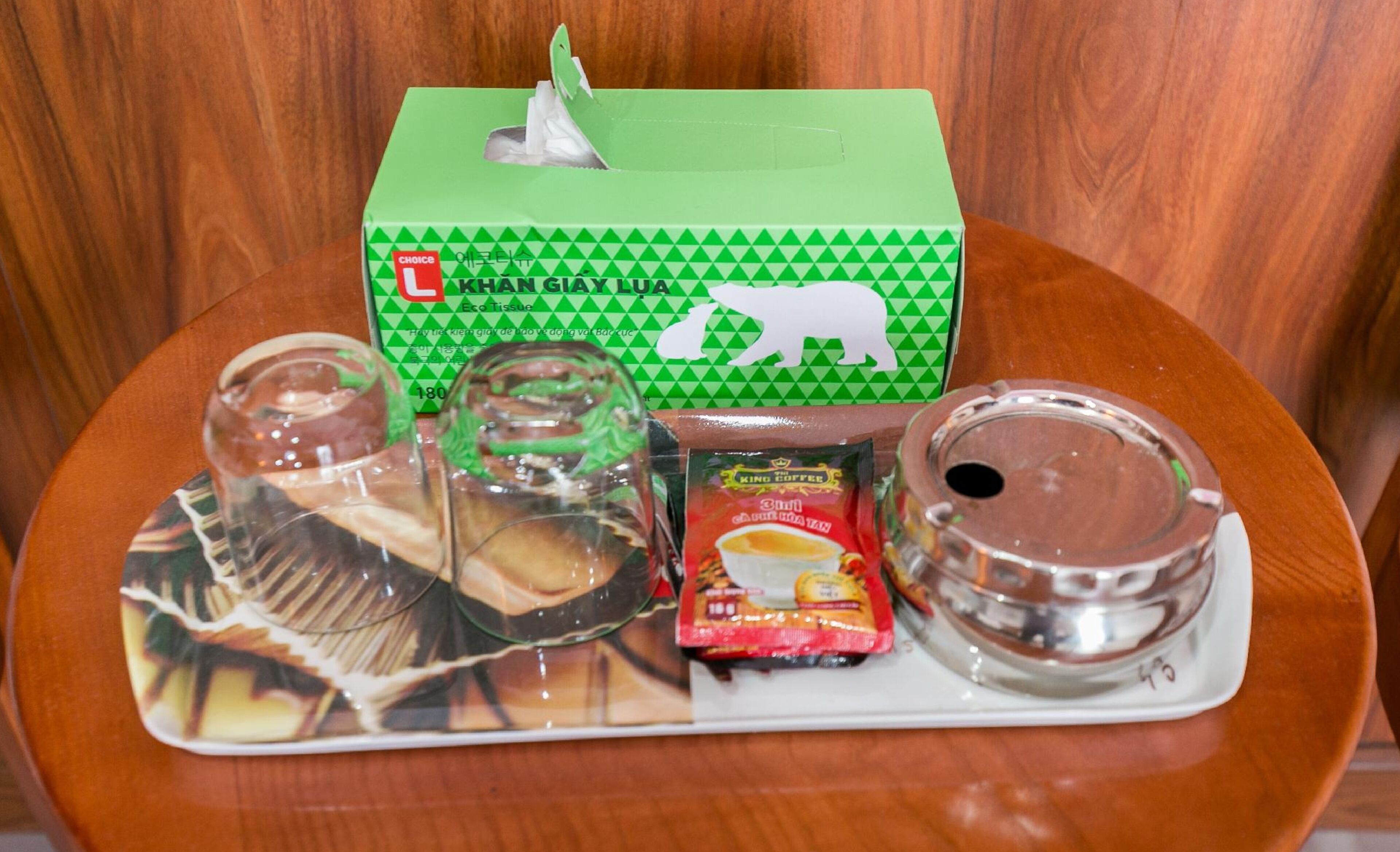 Una bandeja con una caja de pañuelos, un vaso, un paquete de café y un recipiente.