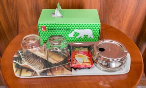 Una bandeja con una caja de pañuelos, un vaso, un paquete de café y un recipiente.