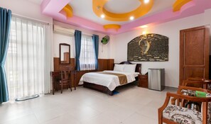 Habitación de hotel con cama, escritorio, silla y refrigerador.