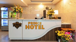 A hotel reception desk with a marble wall, a clock, and a floral arrangement. - Prince Hotel (Ho Chi Minh City)