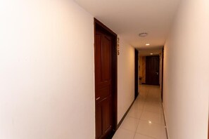 Passadís estret amb una porta de fusta i un senyal amb un número, que condueix a una habitació.