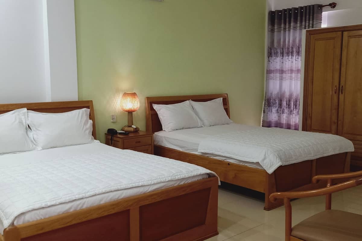 Two wooden beds with white bedding, a nightstand with a lamp, and a wardrobe.