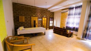 A room with a bed, a wooden chair, a bathtub, and a stone wall. - Dong Phuong Hotel (Quy Nhon Nam)