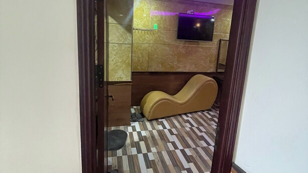 A room with a checkered floor, a television mounted on the wall, and a massage chair. - Hoa Anh Dao 2 Hotel (Ho Chi Minh City)