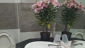 A bathroom with a white sink, a mirror, and two potted plants. - Hoa Anh Dao 2 Hotel (Ho Chi Minh City)