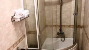 Un baño con ducha de mampara de vidrio, un inodoro y un perchero para toallas.