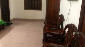 Una habitación con suelo de baldosas, una puerta de madera, una ventana con rejas y un televisor colocado en la pared.