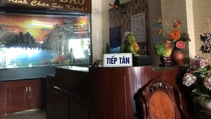 A hotel reception desk with a sign reading "HOTEL HÒNG ĐÀO" and a "TIẾP TÃN" sign.