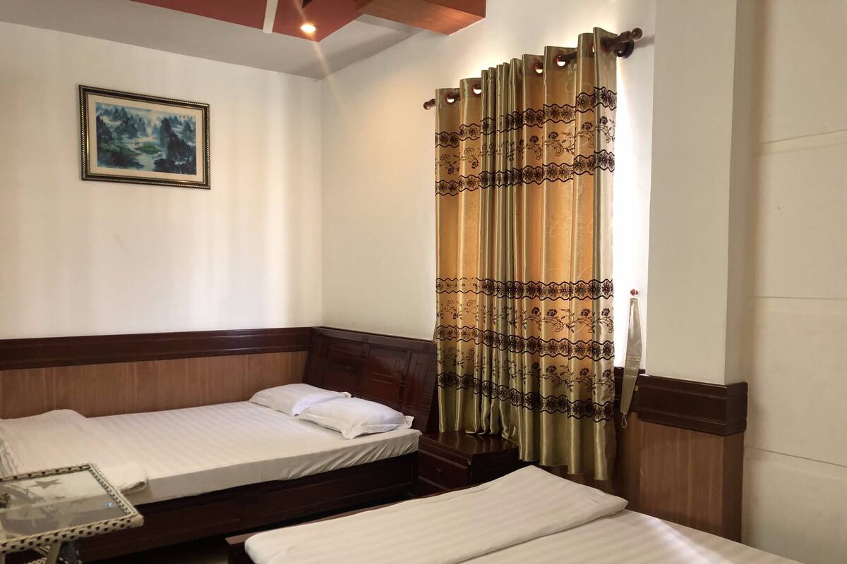 Una habitación con dos camas de madera, una mesita y un cuadro en la pared.