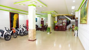 A hotel lobby with a reception desk, a staircase, and several scooters parked in the foreground. - Thanh Tung Hotel (Can Tho)