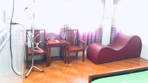 Een woonkamer met een aan de muur bevestigde televisie, een bank, een tafel en stoelen.