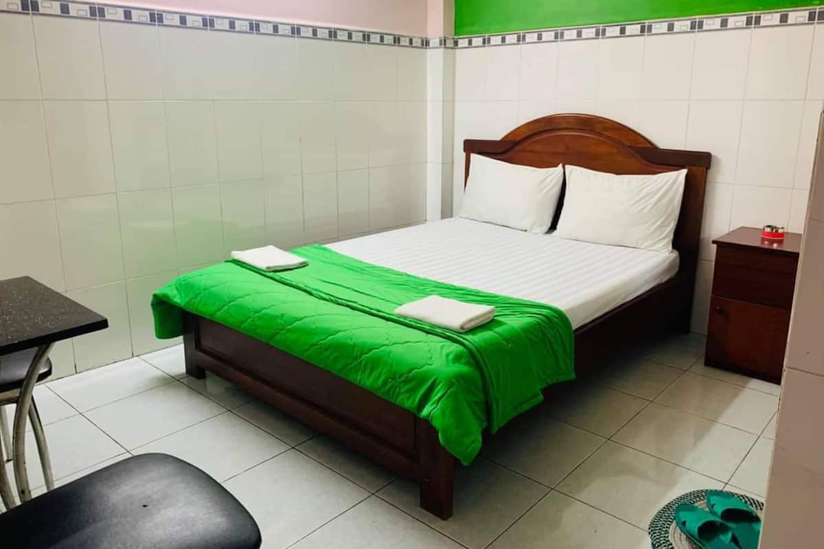 Une chambre d’hôtel avec un lit, une petite table, une chaise et une table de chevet.