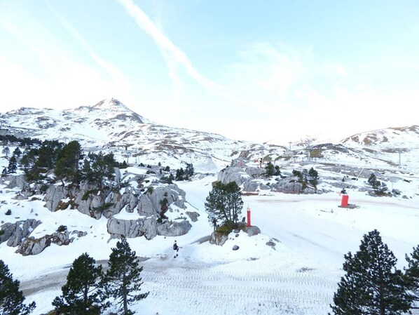 A snowy mountain landscape with rocky outcrops and sparse trees.