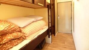 Ein kleines Zimmer mit Etagenbett, Tür und Holzboden.