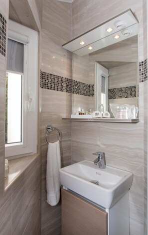 A bathroom with a white sink, a towel rack, a mirror, and a window. - Apartment Mali Skoj (Dubrovnik)