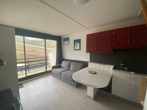 Une cuisine moderne avec une table à manger, des armoires rouges et une grande fenêtre donnant sur un chantier de construction.