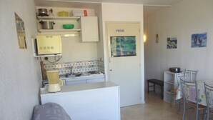 A compact kitchen with a refrigerator, stove, and a small dining area with a table and chairs. - Family studio for 6, ski-in/out, balcony, free parking, ski locker (Arette)