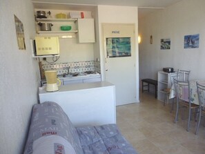A compact kitchen with a refrigerator, stove, and a small dining area with a table and chairs.