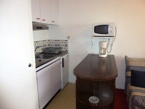 A compact kitchenette with a microwave, coffee maker, and a small sink.
