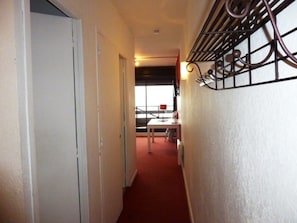 En smal hall med en dörr på vänster sida, ett fönster på höger sida och ett bord med stolar längre in i hallen.
