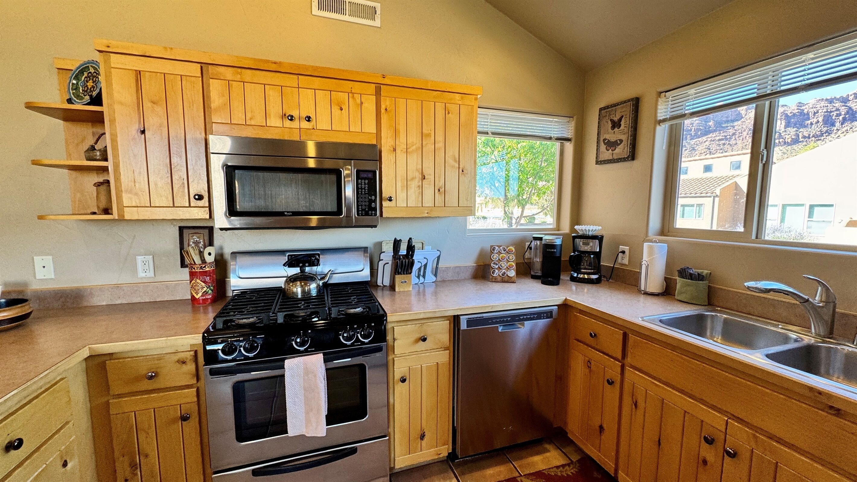 A kitchen with wooden cabinets, a stainless steel stove, a microwave, and a dishwasher.