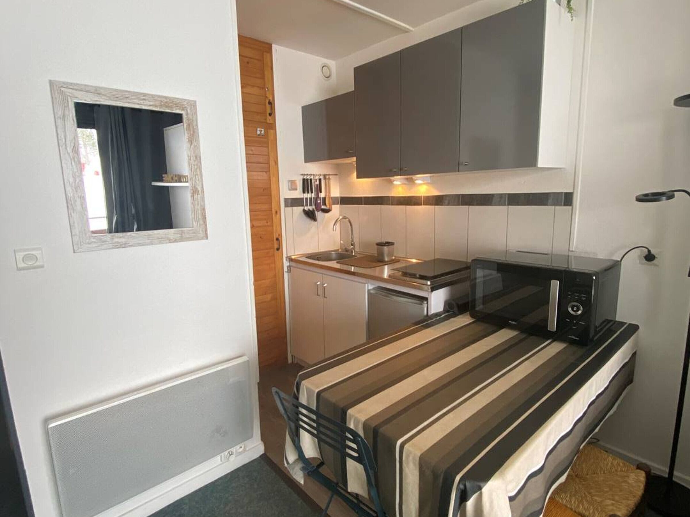 A compact kitchenette with a microwave, sink, and cabinets.