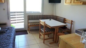Een kamer met een bank, een tafel, een televisie en een kast.