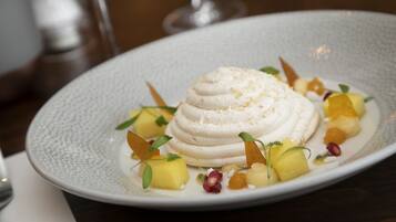 A dessert on a plate with fruits and garnishes.