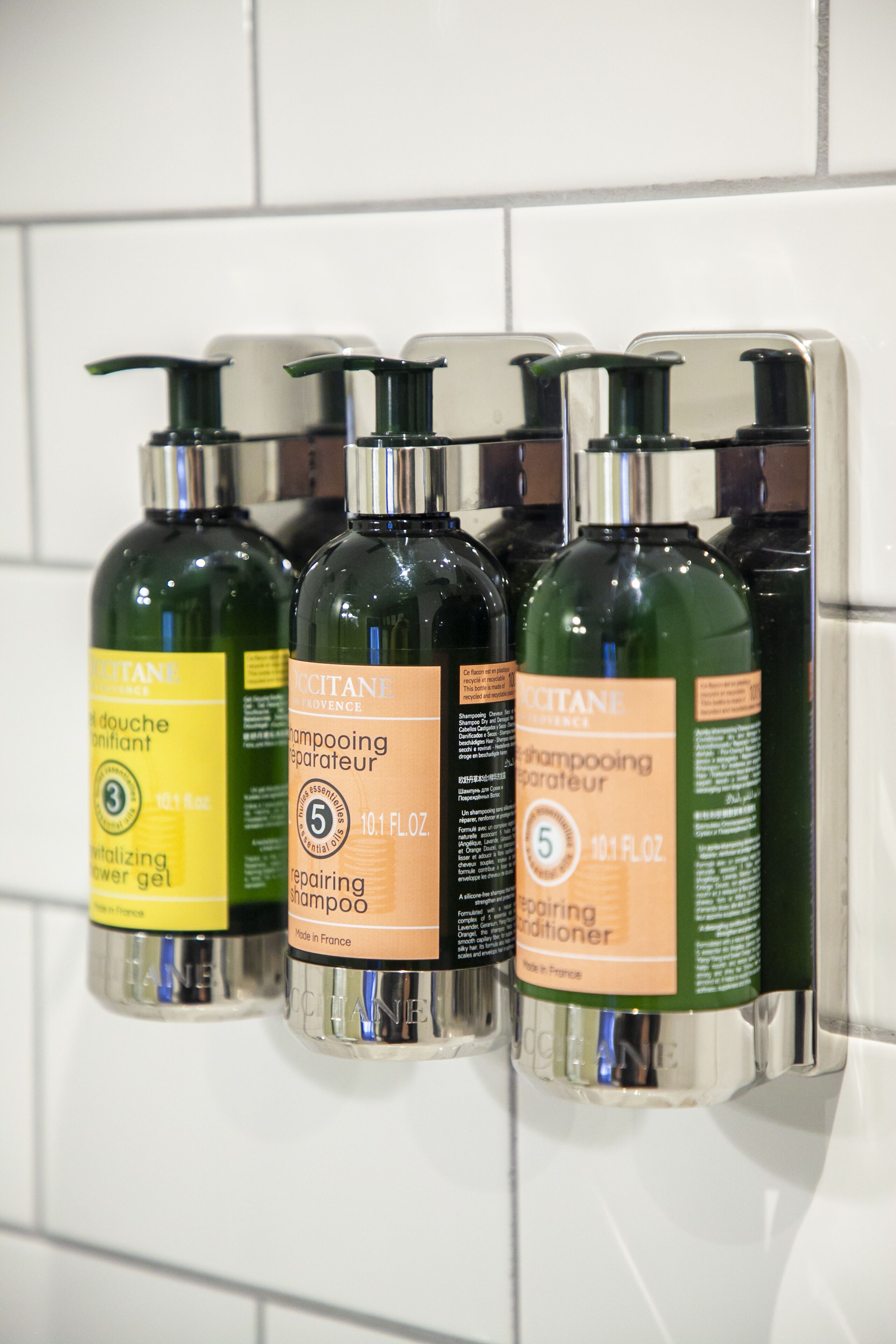 A set of four bottles of hair care products mounted on a wall.