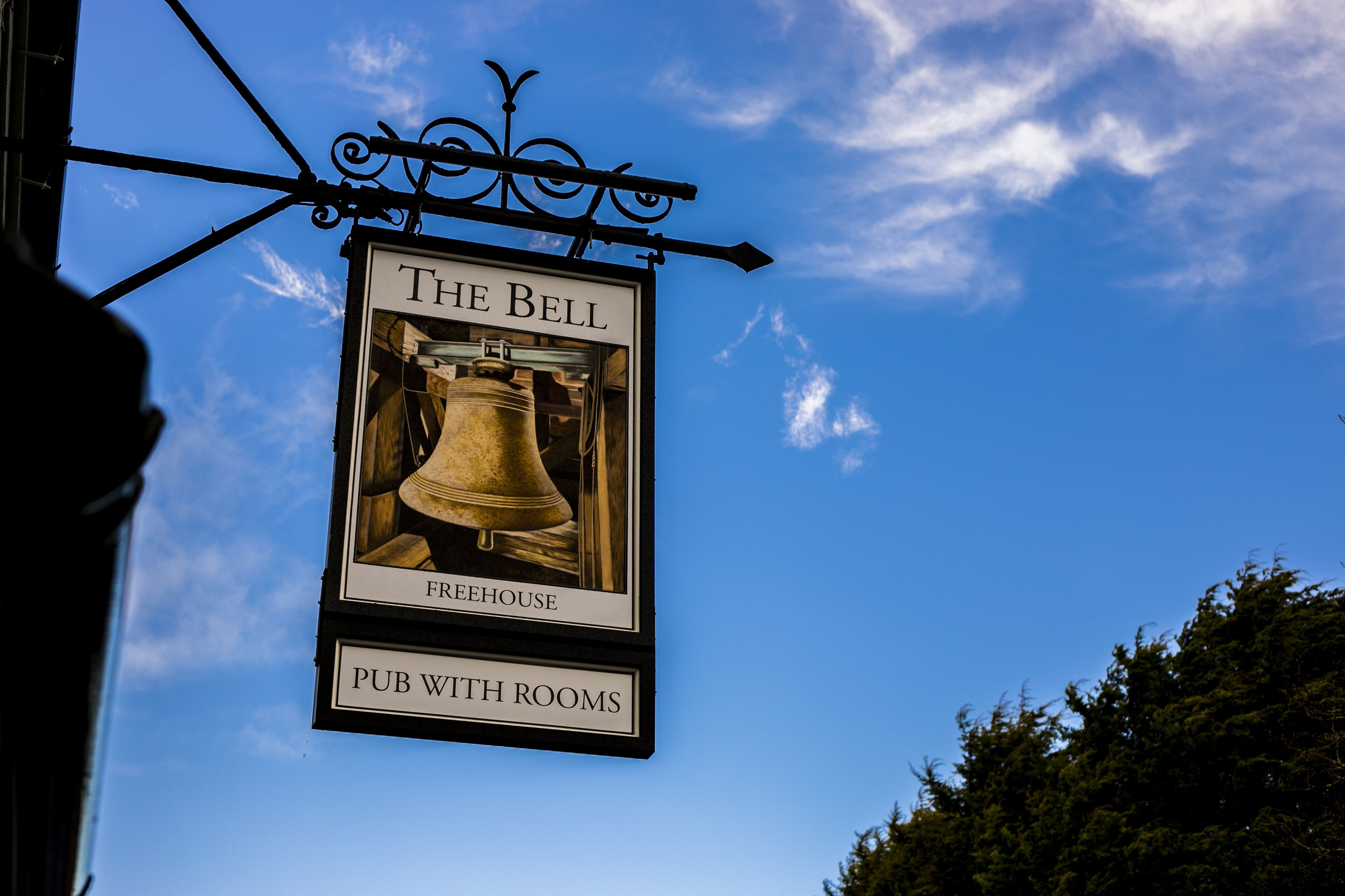 A pub sign with a bell and the words "The Bell Freehouse Pub with Rooms".