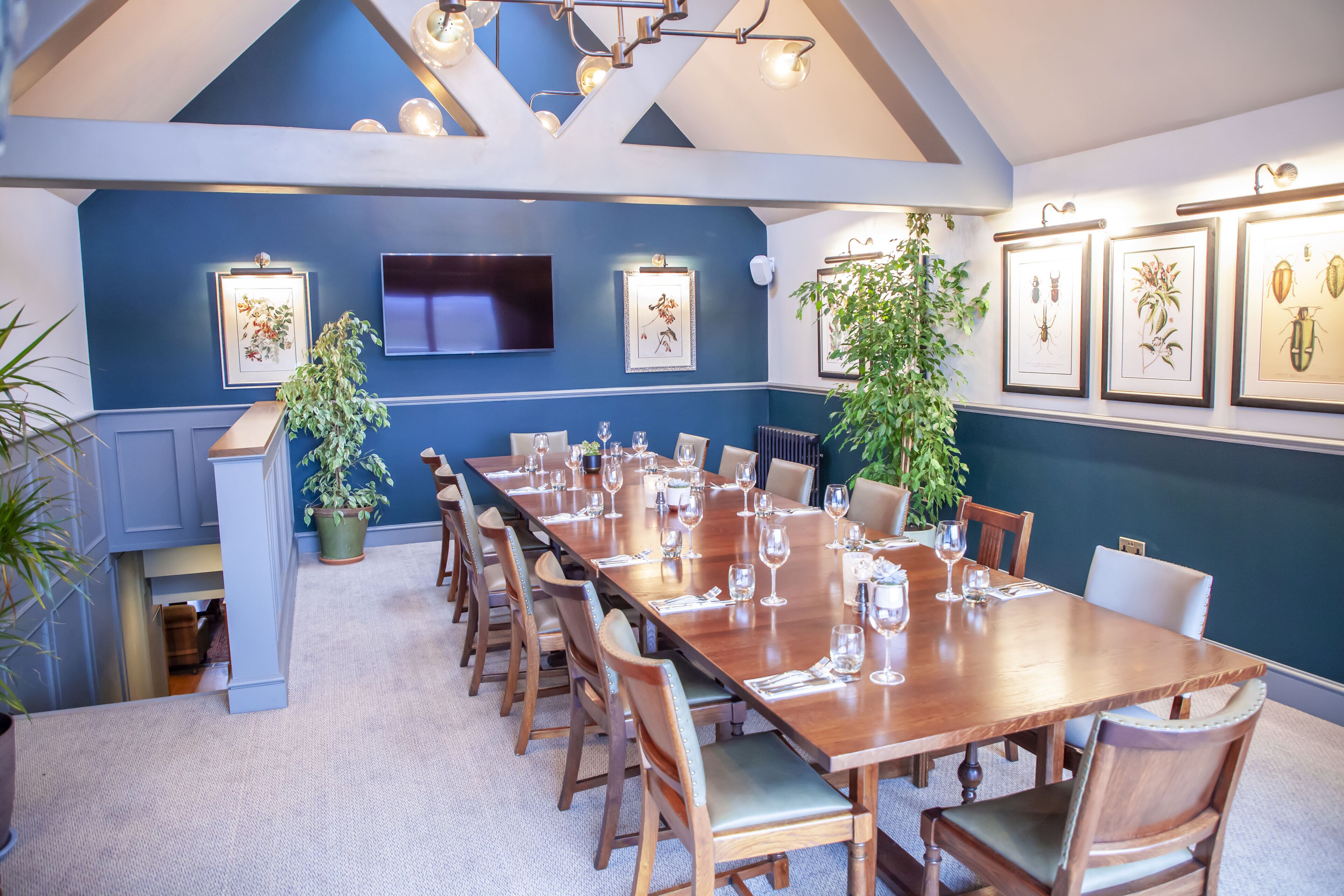 A conference room with a long wooden table, chairs, and framed botanical illustrations on the wall.