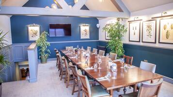 A conference room with a long wooden table, chairs, and framed botanical illustrations on the wall.