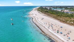 A coastal beach with boats, beachgoers, and buildings in the background. - LIGHTHOUSE A311 - Gorgeous views from top floor Sanibel condo (Sanibel)