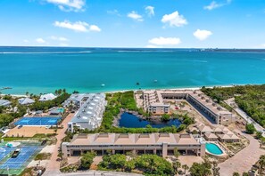 Vue aérienne d’un complexe hôtelier doté d’une piscine, de courts de tennis et d’une plage.