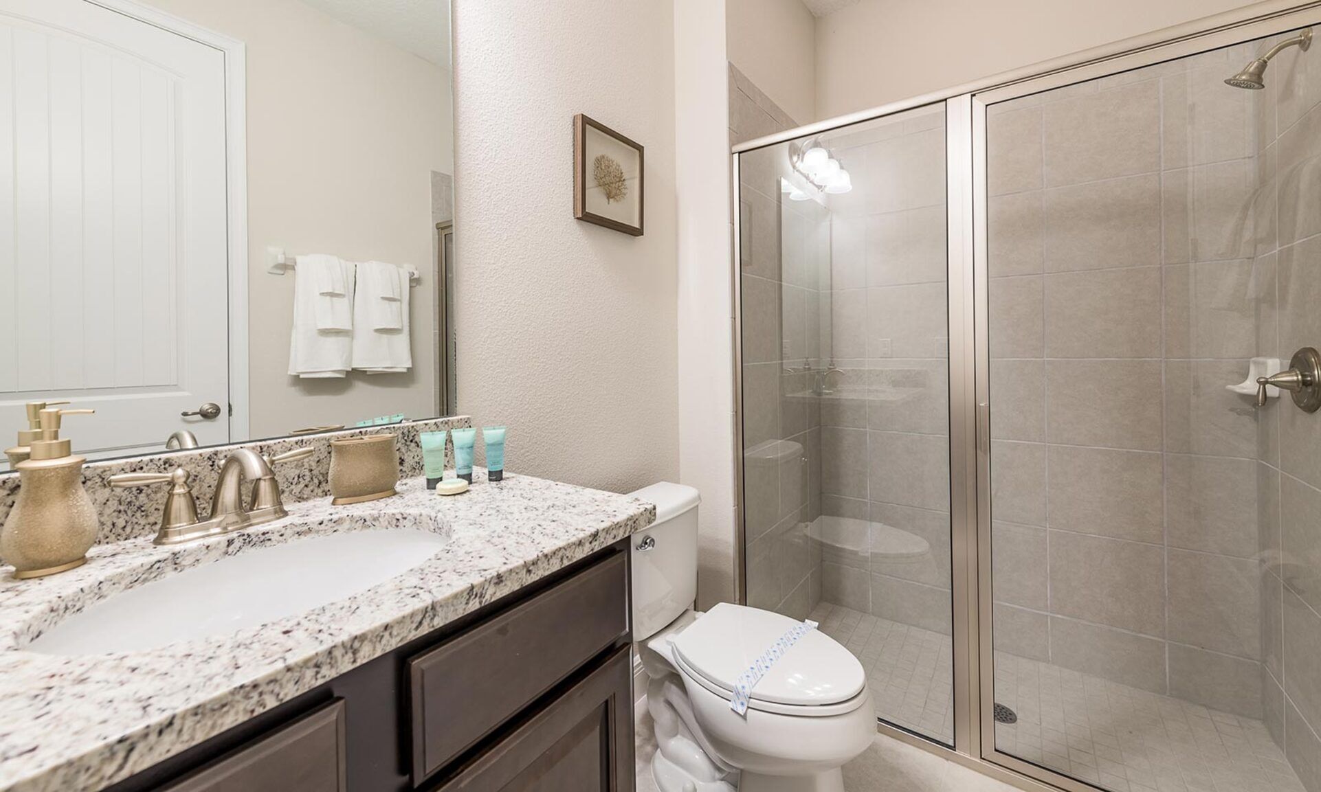 A bathroom with a marble sink, a toilet, and a glass-enclosed shower.
