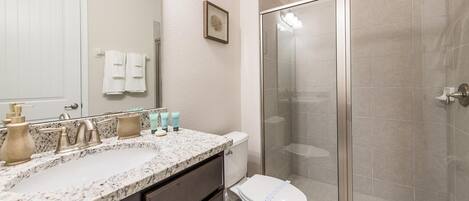 A bathroom with a marble sink, a toilet, and a glass-enclosed shower.