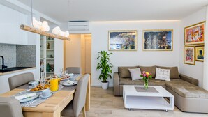 A modern living room with a dining area, a sofa set, a coffee table, and a potted plant. - Apartments Lazarin (Dubrovnik)