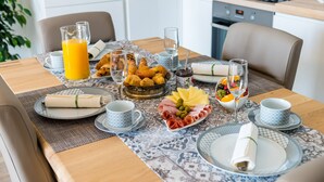 A breakfast setting with croissants, cheese, ham, and fruit on a table with a patterned tablecloth. - Apartments Lazarin (Dubrovnik)