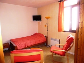 Cozy retreat with a bed, TV, nightstand, chair, and floor lamp.