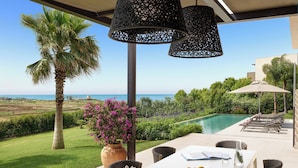 A dining area with a view of the sea, a pool, and lush greenery. - Rocco Forte Private Villas (Sciacca)