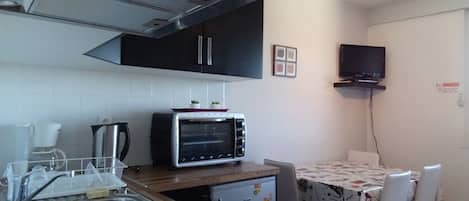 A compact kitchen with a built-in oven, a coffee maker, and a small refrigerator.