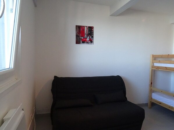 A room with a black sofa, a wooden bunk bed, and a small painting on the wall. - Cozy Studio for 4 with Kitchen, Free Parking, Ski Locker - La Pierre St Martin (Arette)