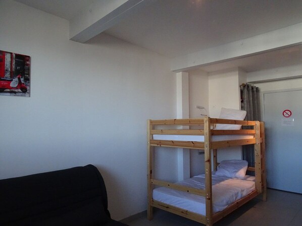 A bunk bed room with a black couch, a painting on the wall, and a door with a no smoking sign. - Cozy Studio for 4 with Kitchen, Free Parking, Ski Locker - La Pierre St Martin (Arette)