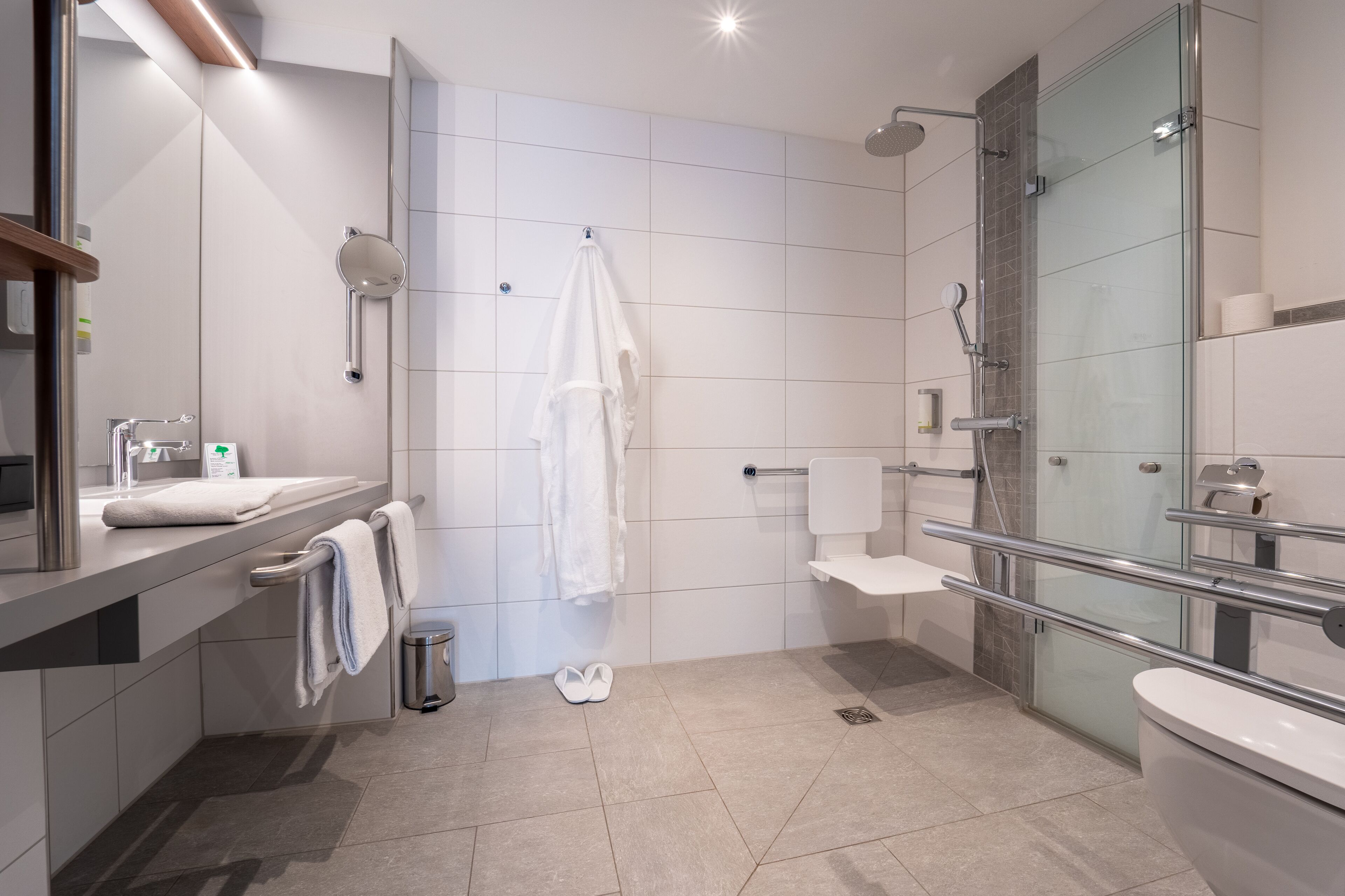 Un baño moderno con ducha de vidrio, inodoro y lavamanos con espejo.