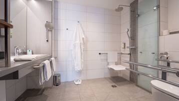 Un baño moderno con ducha de vidrio, inodoro y lavamanos con espejo.