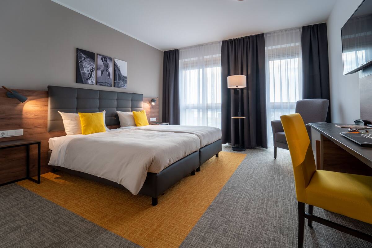 Una habitación de hotel moderna con una cama grande, un escritorio y una silla.