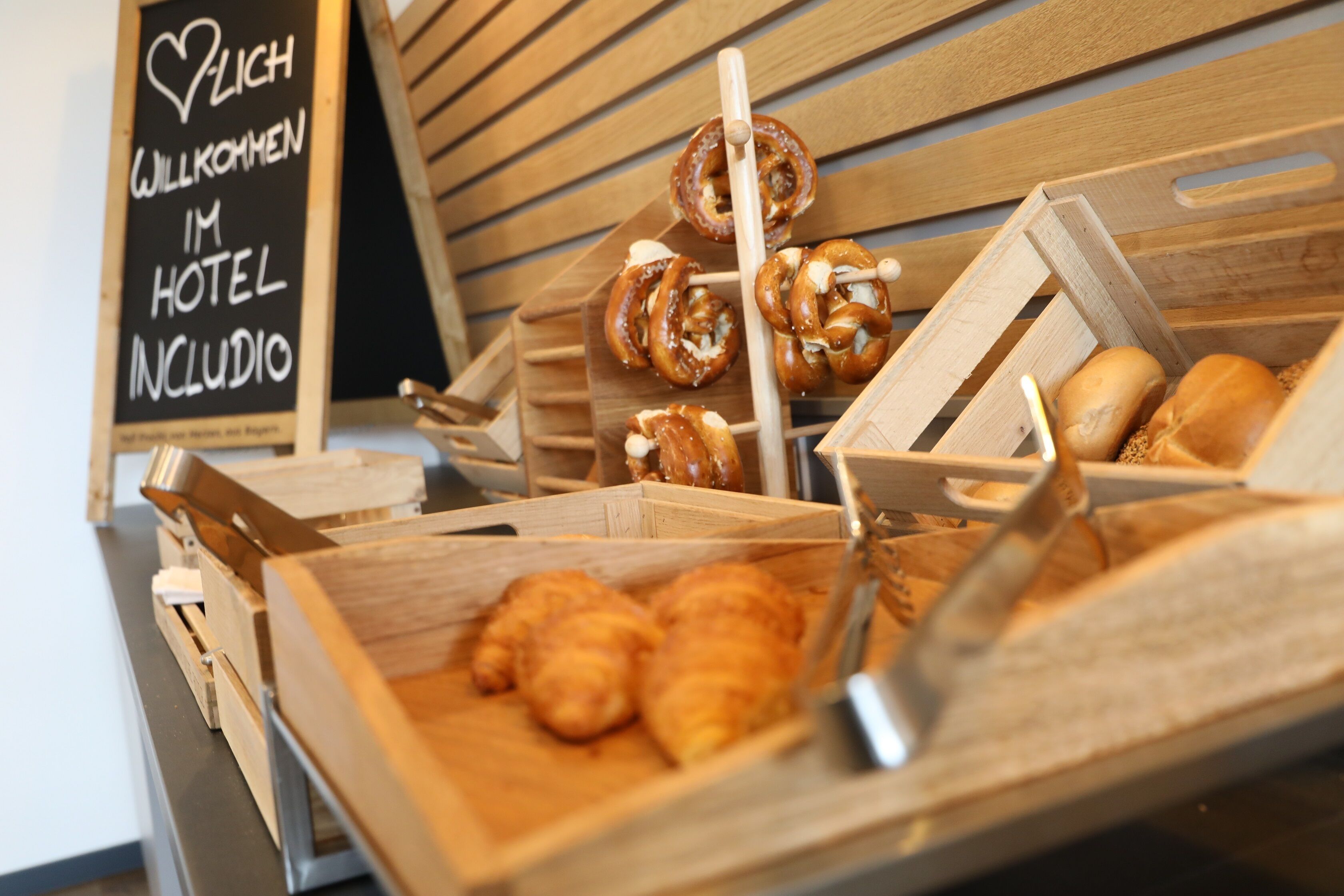 Una variedad de productos horneados, como pretzels, croissants y pan, presentados en cajas de madera.